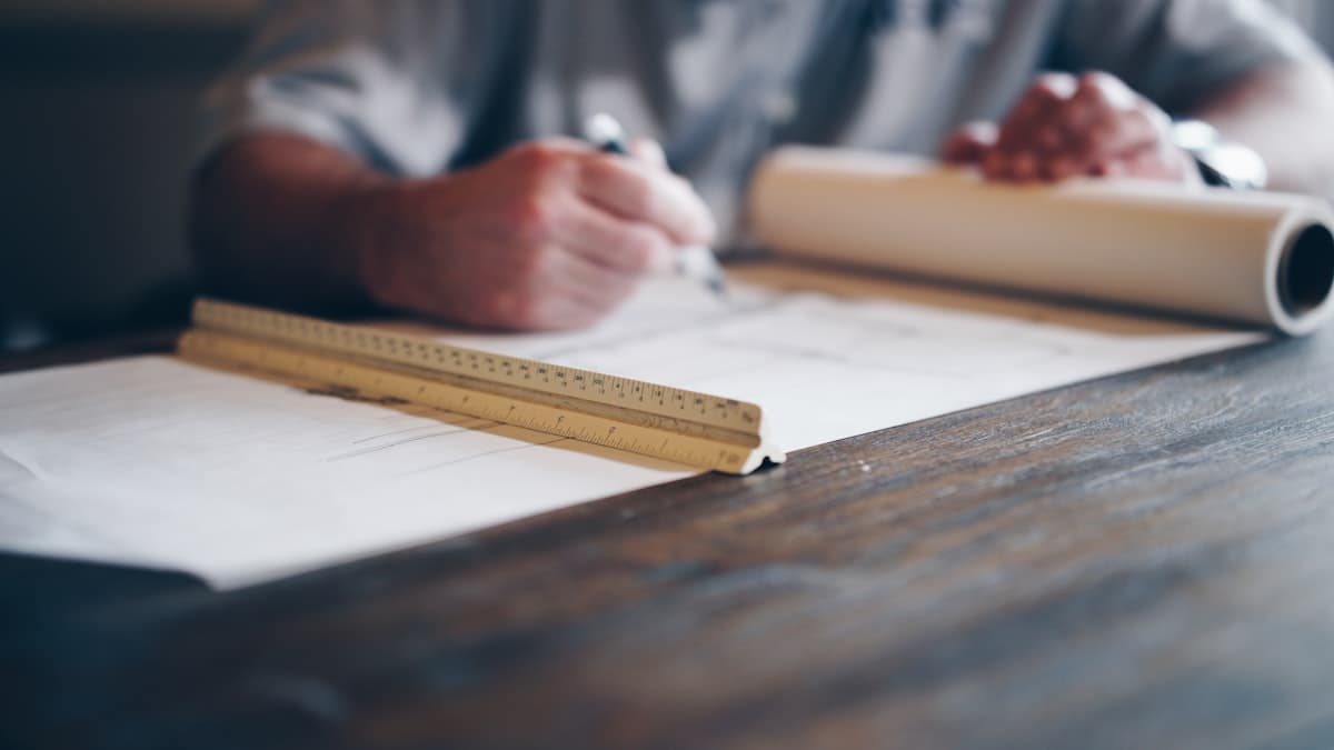 Hands sketching an architectural concept with a ruler