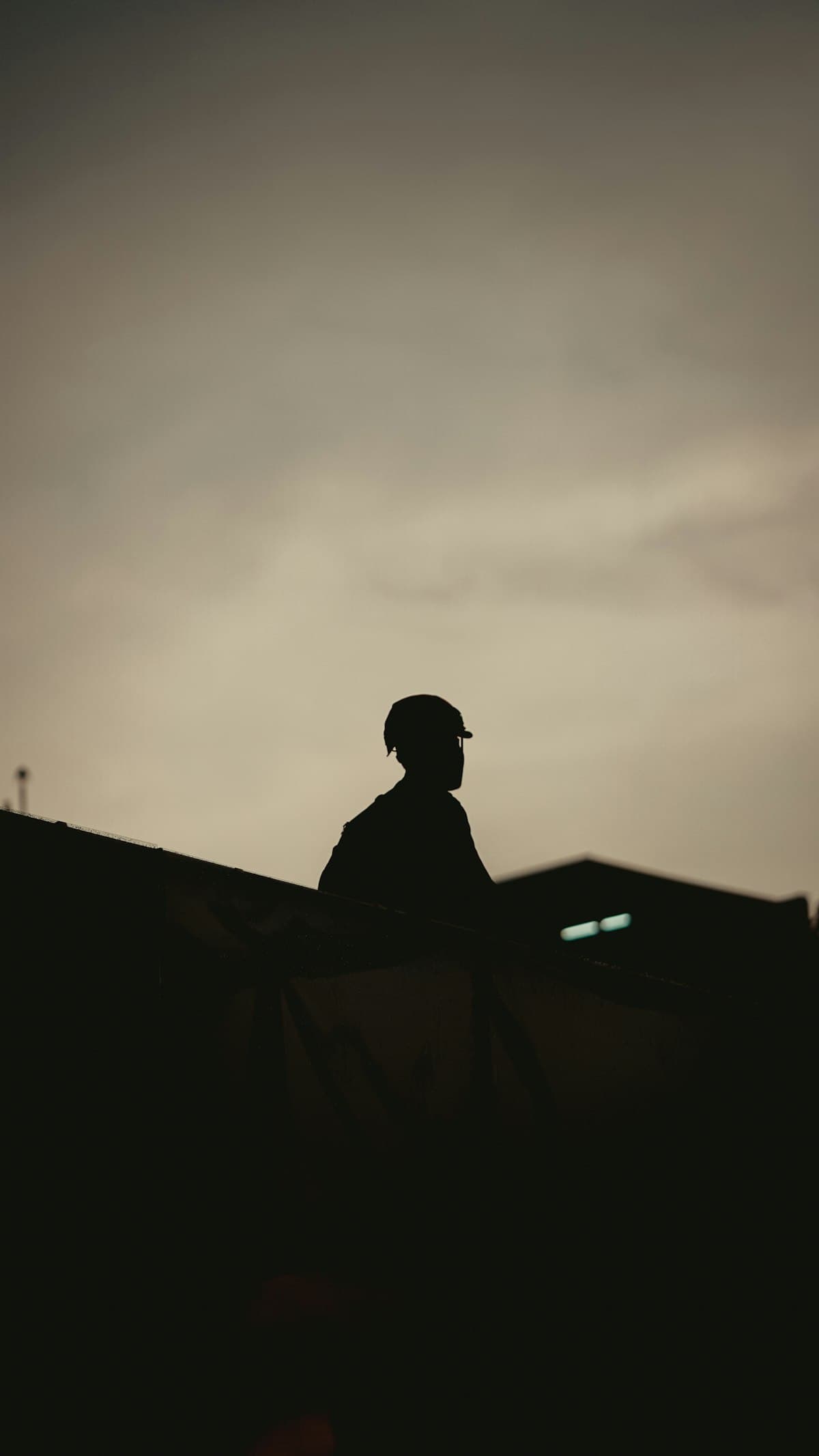 Silhouette of a supervisor in a hardhat at a construction site at dusk