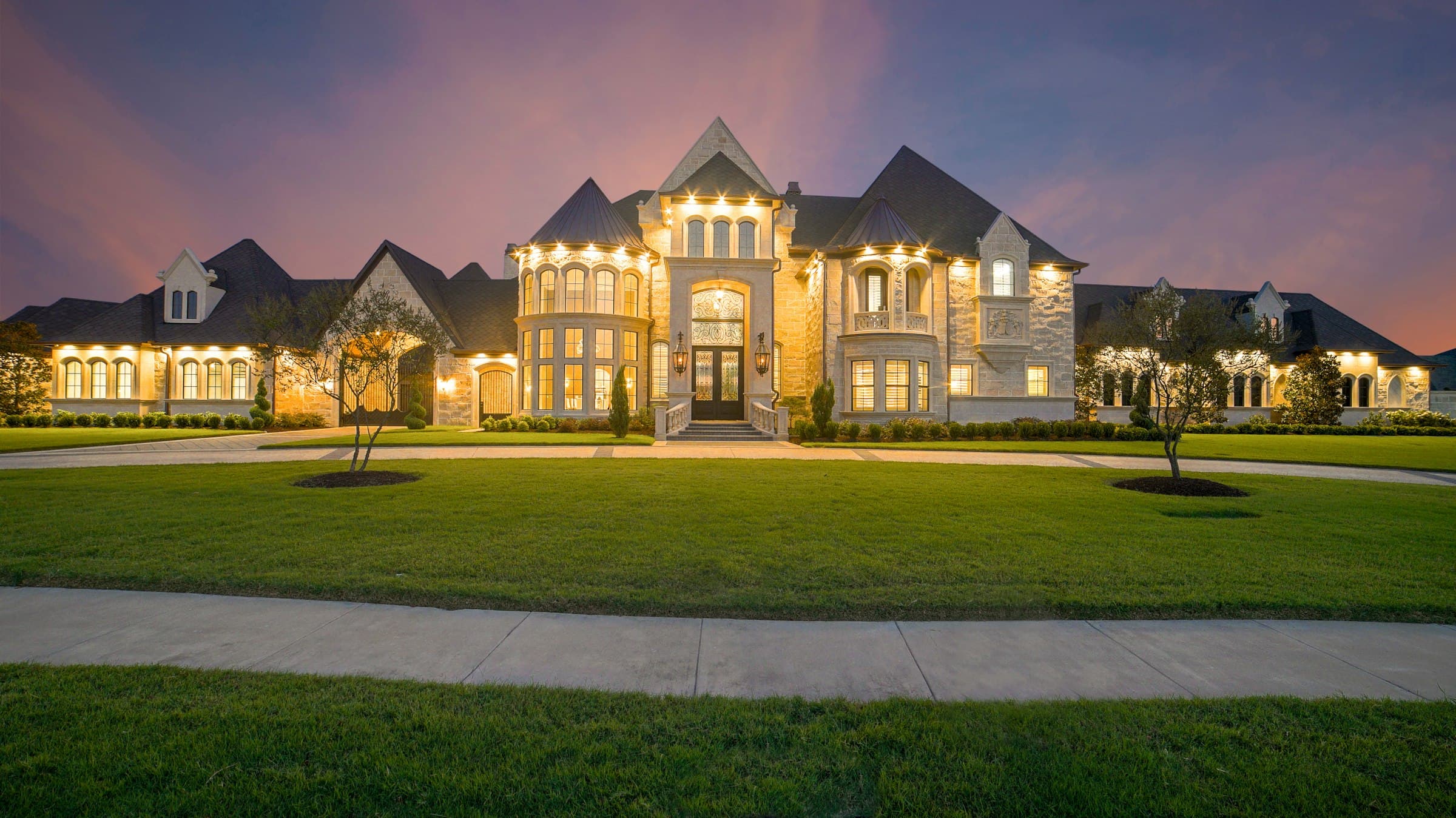 Grand mansion exterior illuminated at dusk