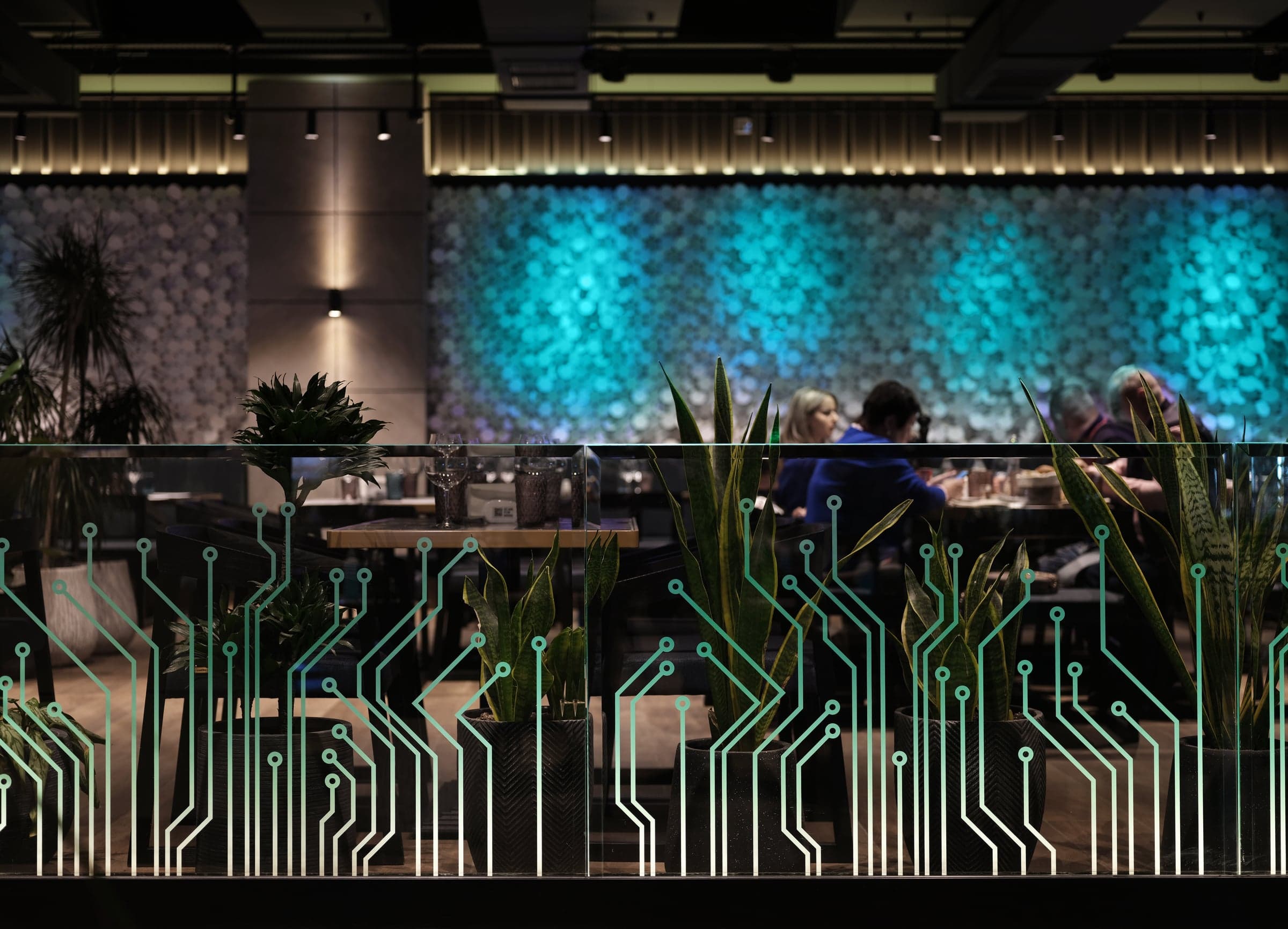 Restaurant dining room with lush plants behind a glass partition